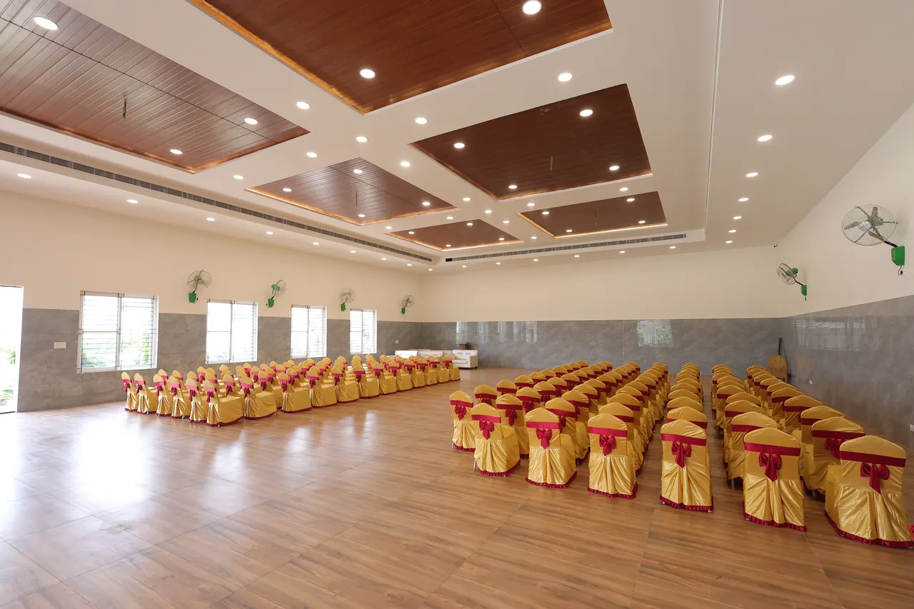 The mini banquet hall at Sree Raaga Resorts set with rows of gold chairs