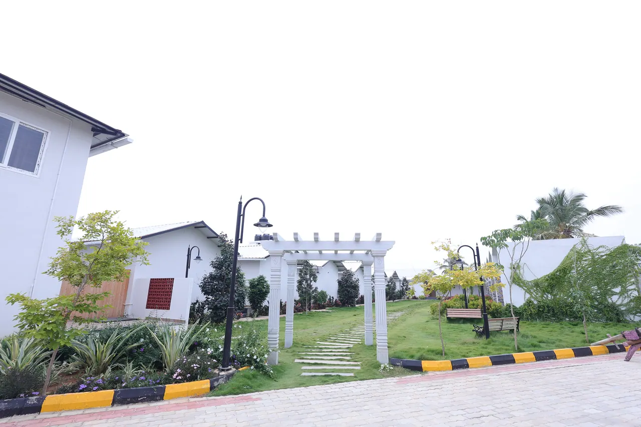 The pergola garden at Sree Raaga Resorts, with a stepping-stone path across the lawn and a bench under the trees