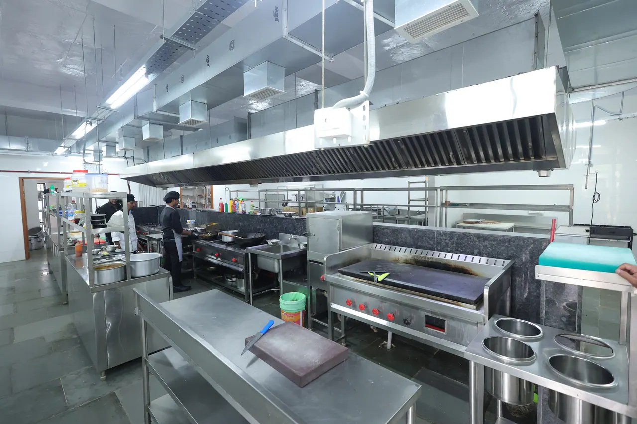The commercial kitchen at Sree Raaga Resorts seen wide, with prep counters and range
