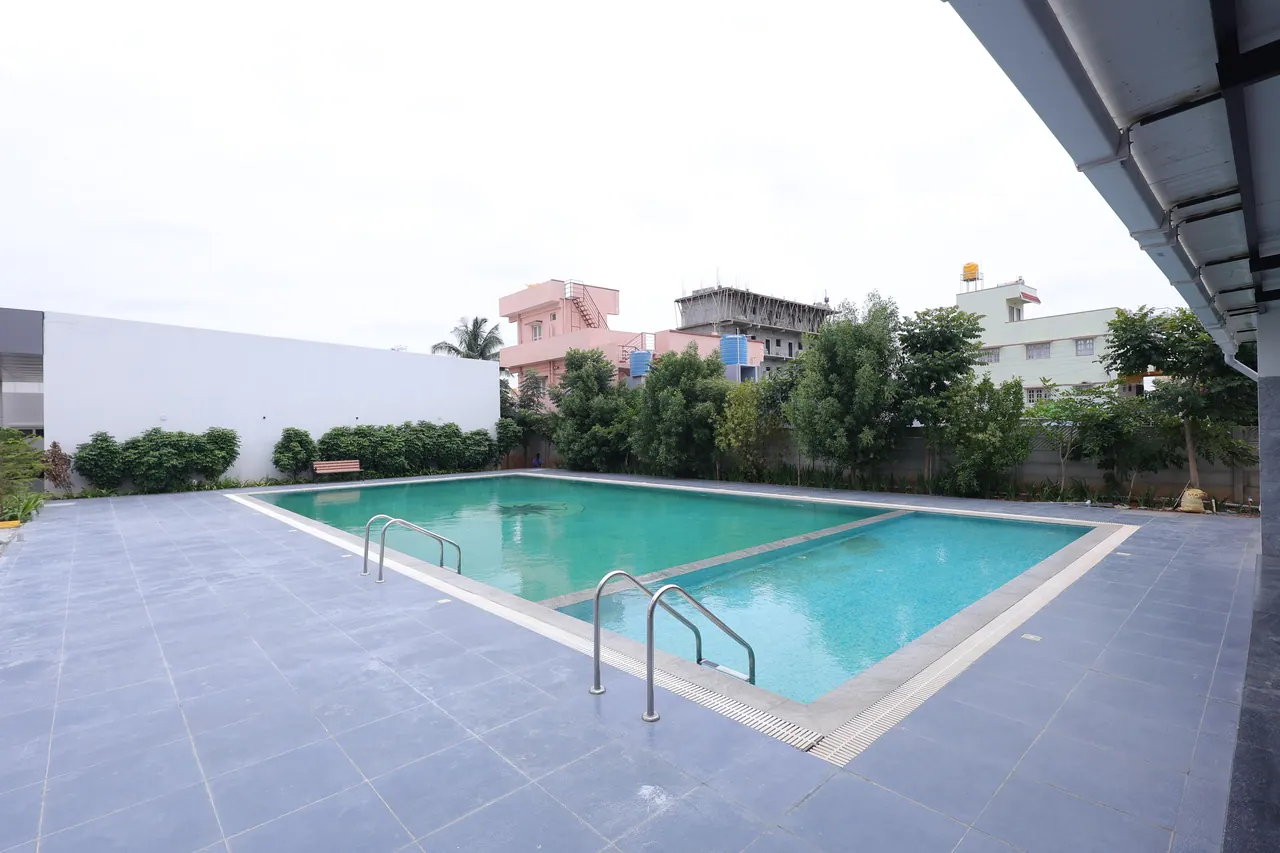 The swimming pool and tiled deck at Sree Raaga Resorts on a bright day