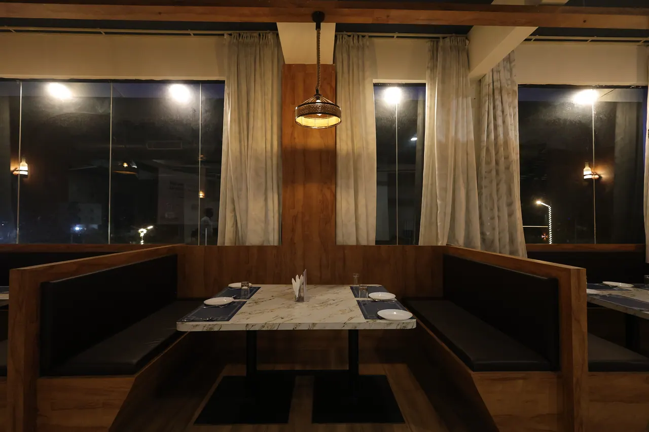 A laid restaurant booth table beside a window at night