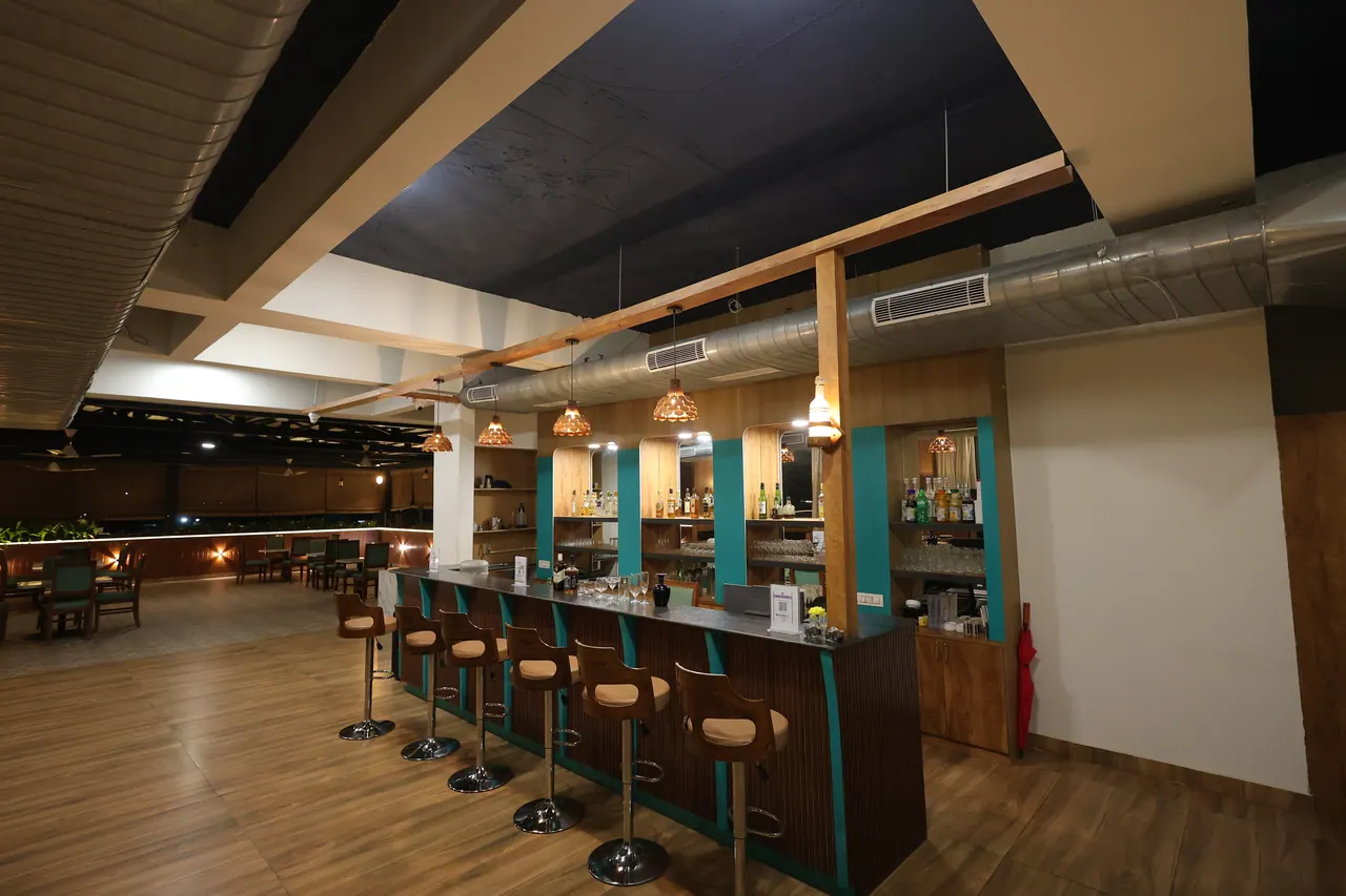 A long bar counter with upholstered stools and teal panelling at the sports bar