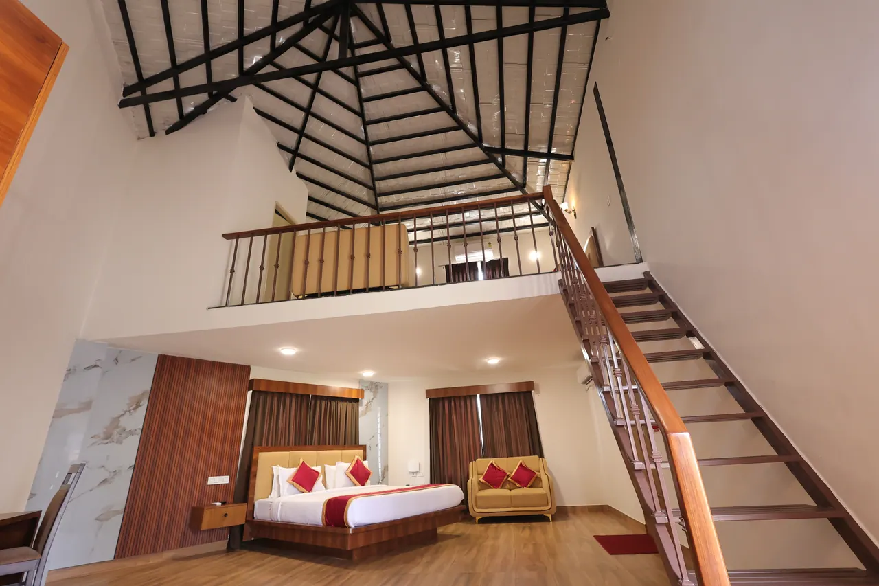 The double-height interior of the duplex at Sree Raaga Resorts, open to exposed roof trusses with a mezzanine above