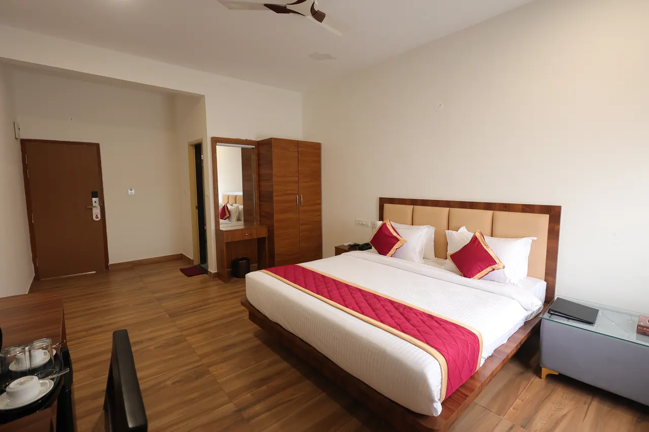 Executive room with a king bed on a low wooden platform, cream walls and a curtained window