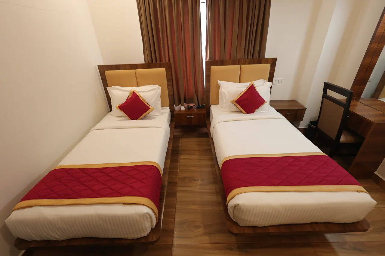 Detail of a made single bed with a maroon and gold runner in an executive room