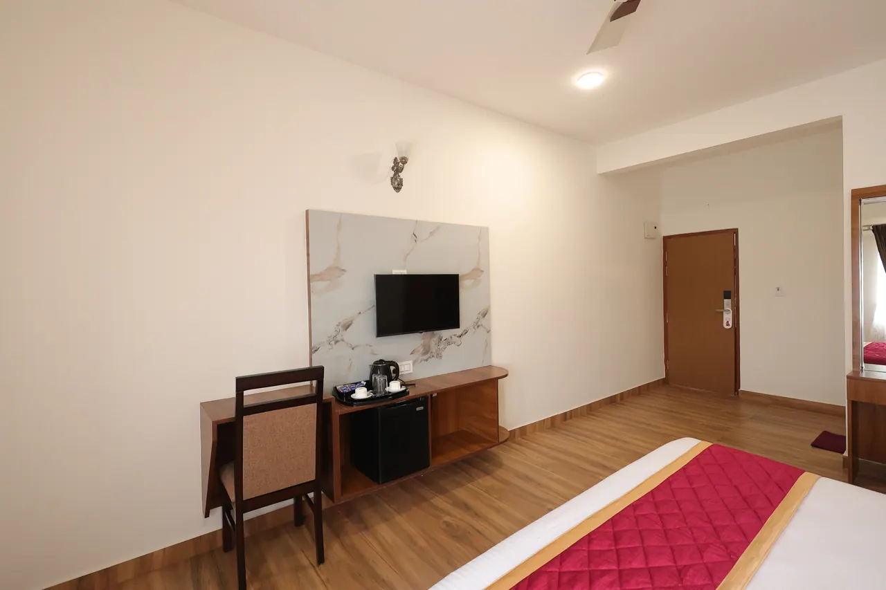 Desk and chair beside a console holding a kettle, tea tray and mini fridge in an executive room