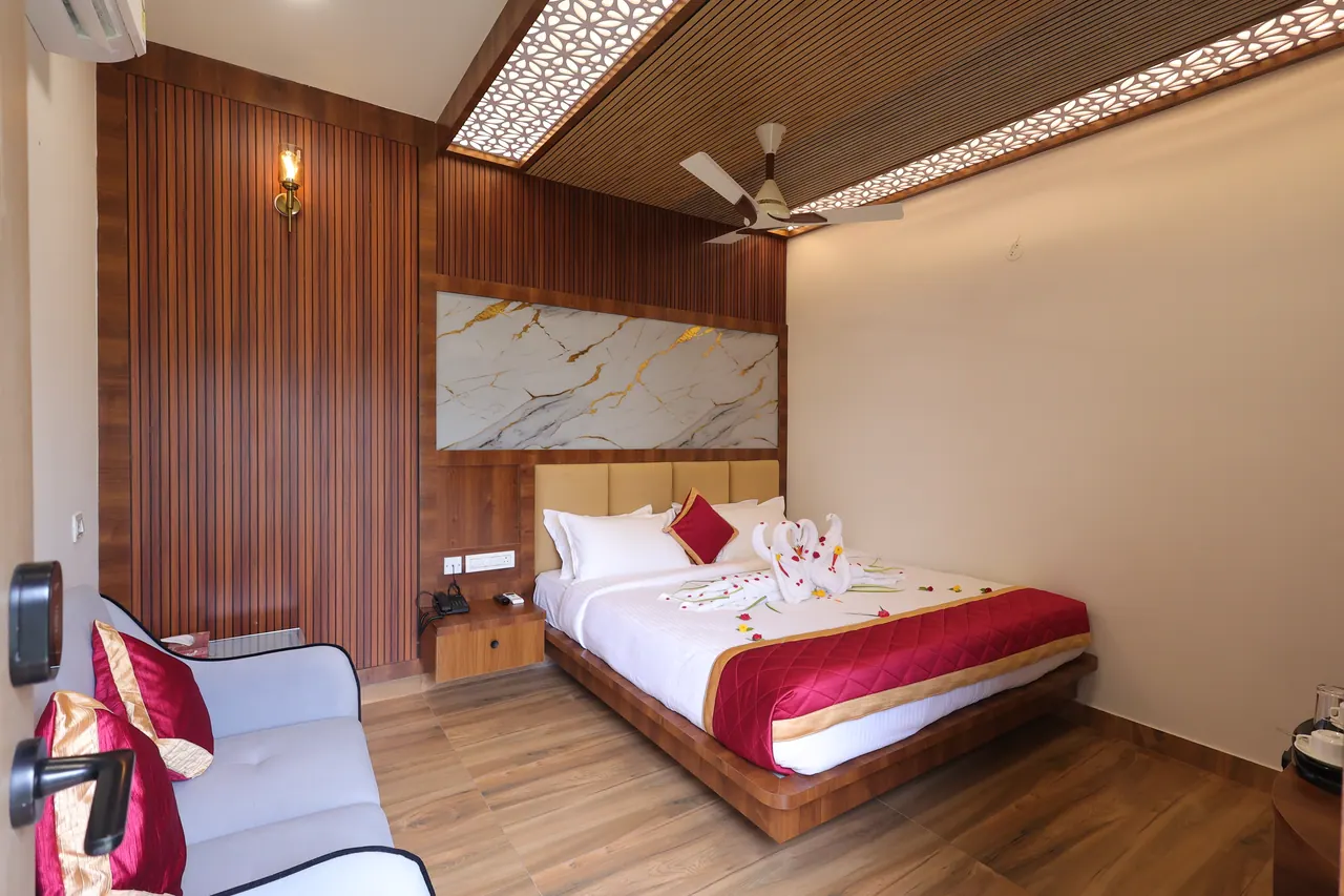 Luxury villa bedroom with a king bed on a low wooden platform, teak panelling and a grey sofa by the window