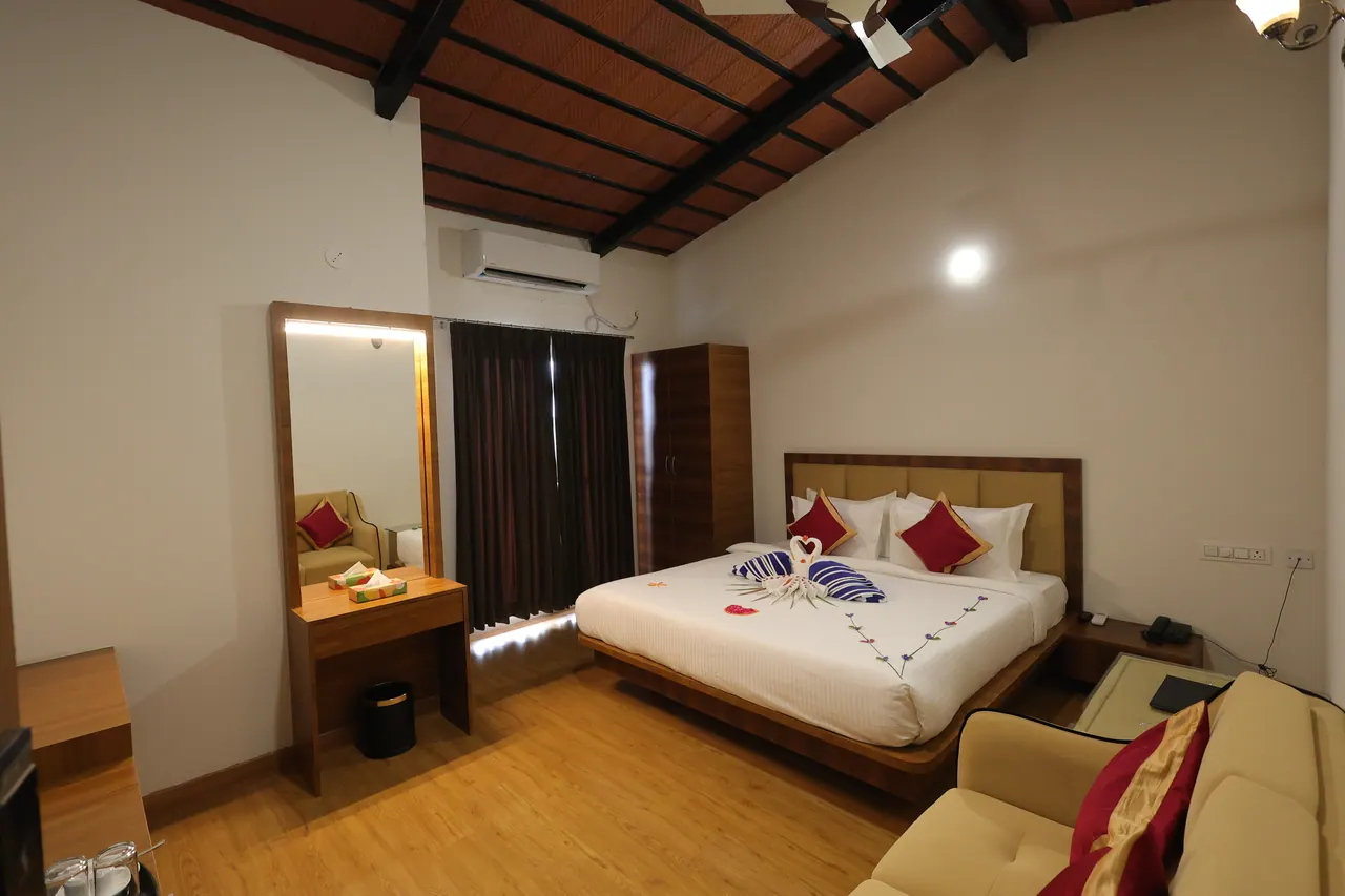 Villa bedroom open to a pitched roof with dark exposed timber rafters and terracotta tile